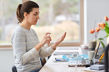 Image showing woman spraying hand sanitizer at home office