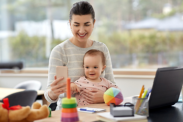 Image showing mother with baby and phone working at home office