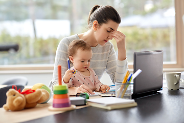 Image showing tired mother with baby working at home office