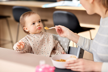 Image showing happy mother feeding baby with puree at home