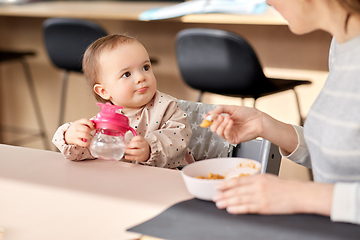 Image showing happy mother feeding baby with puree at home