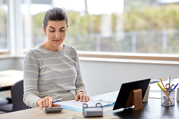 Image showing woman with calculator and papers working at home