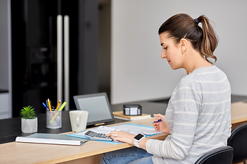 Image showing woman with calculator and papers working at home