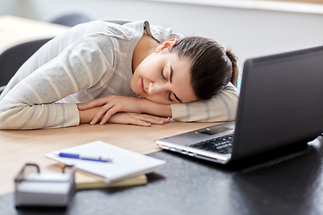 Image showing tired woman sleeping on table with laptop at home