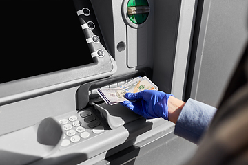 Image showing hand in medical glove with money at atm machine