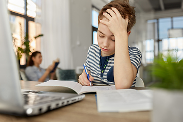 Image showing student boy with book writing to notebook at home