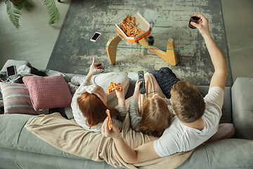 Image showing Family spending nice time together at home, looks happy and cheerful, eating pizza. Top view.