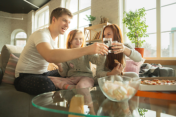 Image showing Family spending nice time together at home, looks happy and excited, eating pizza, watching sport match