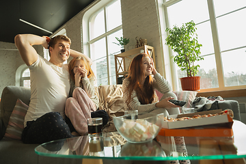 Image showing Family spending nice time together at home, looks happy and excited, eating pizza, watching sport match