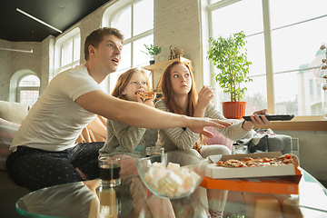 Image showing Family spending nice time together at home, looks happy and excited, eating pizza, watching sport match