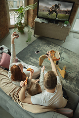 Image showing Family spending nice time together at home, looks happy and excited, eating pizza, watching football match