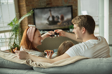 Image showing Family spending nice time together at home, looks happy and excited, eating pizza, watching football match