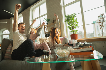 Image showing Family spending nice time together at home, looks happy and excited, eating pizza, watching sport match