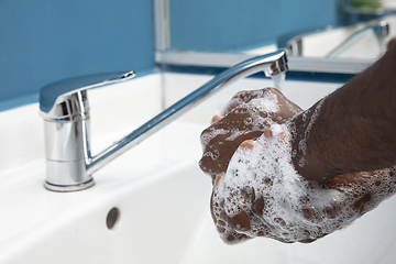 Image showing Man washing hands carefully in bathroom close up. Prevention of infection and pneumonia virus spreading