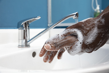 Image showing Man washing hands carefully in bathroom close up. Prevention of infection and pneumonia virus spreading