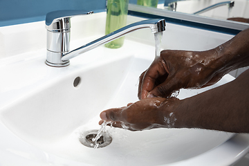 Image showing Man washing hands carefully in bathroom close up. Prevention of infection and pneumonia virus spreading