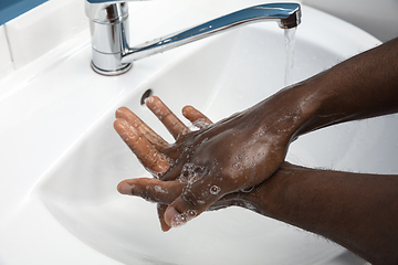 Image showing Man washing hands carefully in bathroom close up. Prevention of infection and pneumonia virus spreading