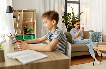 Image showing mother with smartphone and son learning at home