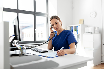 Image showing doctor with computer calling on phone at hospital