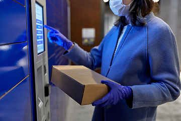 Image showing woman in mask with box at parcel machine