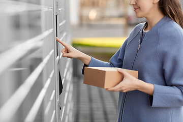 Image showing smiling woman with box at automated parcel machine