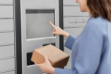 Image showing smiling woman with box at automated parcel machine