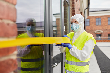 Image showing healthcare worker sealing door with caution tape