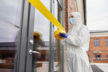 Image showing healthcare worker sealing door with caution tape