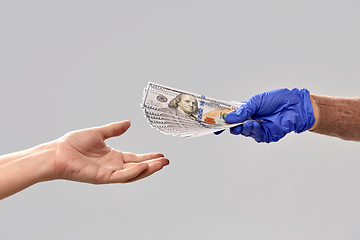 Image showing close up of hand in medical glove giving money