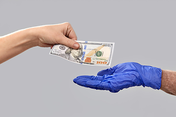 Image showing close up of hand in medical glove giving money