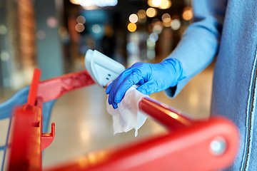 Image showing hand cleaning shopping cart handle with wet wipe