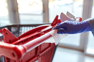 Image showing hand cleaning shopping cart handle with wet wipe