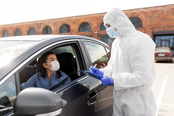 Image showing healthcare worker with clipboard and woman in car