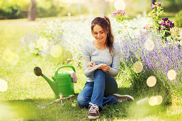 Image showing young woman writing to notebook at summer garden