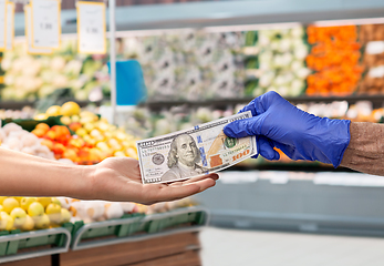 Image showing close up of hand in medical glove paying money