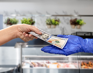 Image showing close up of hand in medical glove giving money