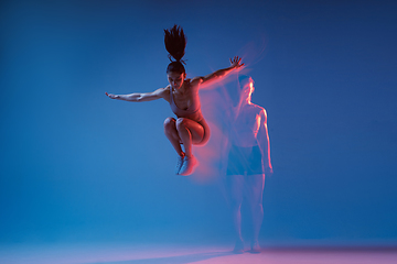 Image showing Caucasian professional female athlete training on blue studio background in neon, mixed light. Muscular, sportive woman.