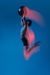 Image showing Caucasian professional female athlete training on blue studio background in neon, mixed light. Muscular, sportive woman.