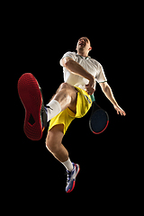 Image showing Young caucasian tennis player in action, motion isolated on black background, look from the bottom. Concept of sport, movement, energy and dynamic.