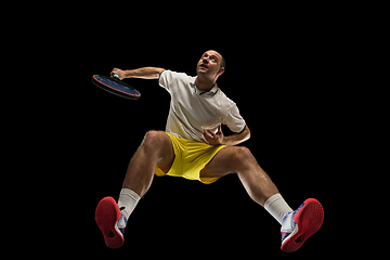 Image showing Young caucasian tennis player in action, motion isolated on black background, look from the bottom. Concept of sport, movement, energy and dynamic.