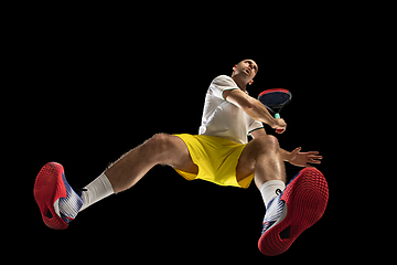 Image showing Young caucasian tennis player in action, motion isolated on black background, look from the bottom. Concept of sport, movement, energy and dynamic.