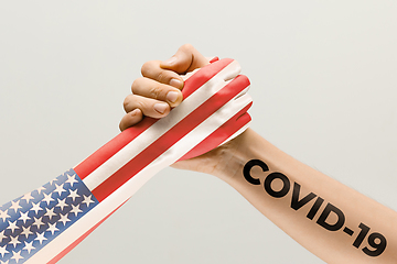 Image showing Human hands colored in flag of United States of America and coronavirus - concept of spreading of virus, fighting.