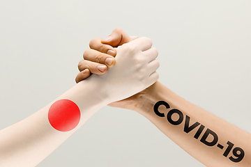 Image showing Human hands colored in flag of Japan and coronavirus - concept of spreading of virus, fighting