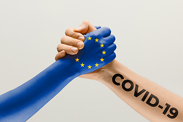 Image showing Human hands colored in flag of Europian Union and coronavirus - concept of spreading of virus, fighting