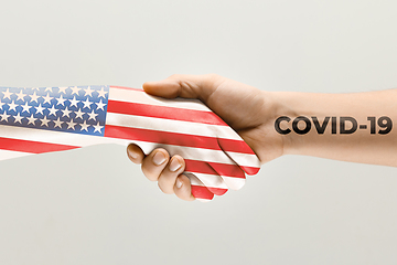 Image showing Human hands colored in flag of United States of America and coronavirus - concept of spreading of virus