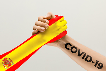 Image showing Human hands colored in flag of Spain and coronavirus - concept of spreading of virus, fighting