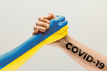 Image showing Human hands colored in flag of Ukraine and coronavirus - concept of spreading of virus, fighting