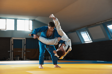 Image showing Two young judo fighters in kimono training martial arts in the gym with expression, in action and motion