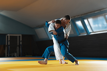 Image showing Two young judo fighters in kimono training martial arts in the gym with expression, in action and motion