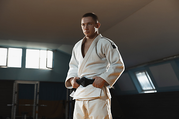 Image showing Young judo fighter in kimono posing comfident in the gym, strong and healthy